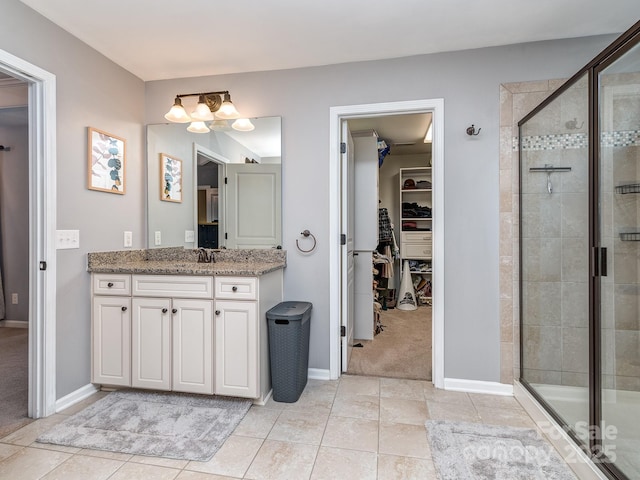 bathroom with a stall shower, vanity, a walk in closet, and baseboards