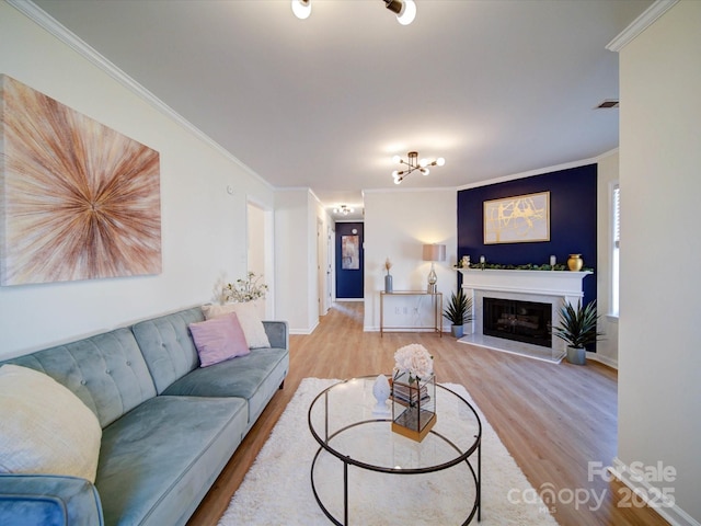 living area featuring visible vents, baseboards, a premium fireplace, ornamental molding, and wood finished floors