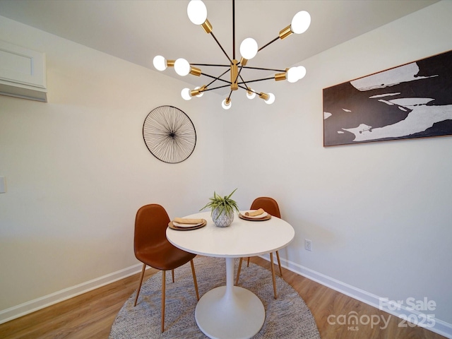 dining space featuring a notable chandelier, wood finished floors, and baseboards