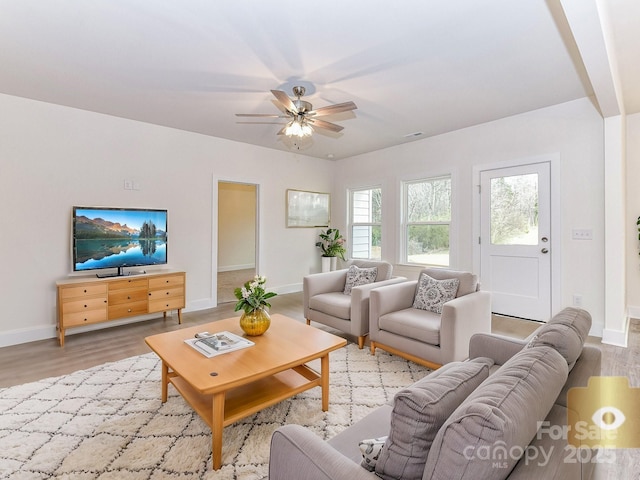 living area featuring visible vents, a ceiling fan, baseboards, and wood finished floors