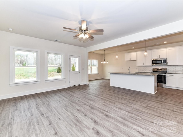 kitchen with light wood finished floors, open floor plan, backsplash, and stainless steel appliances