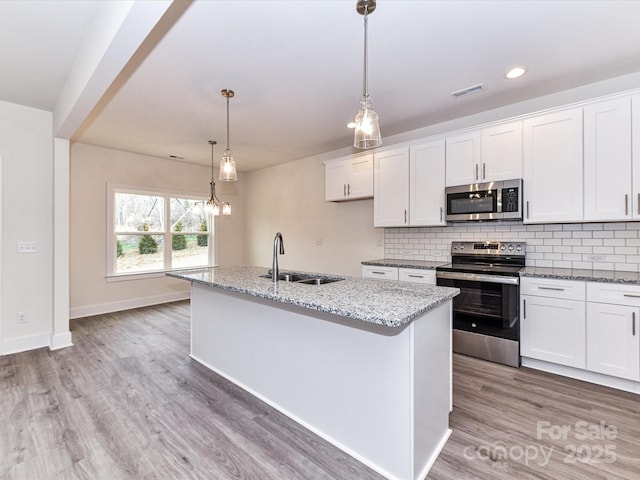 kitchen with decorative backsplash, light wood finished floors, appliances with stainless steel finishes, and a sink