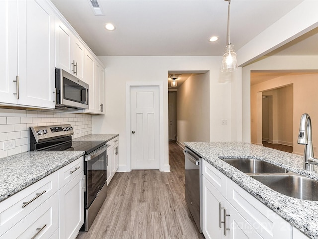 kitchen featuring visible vents, a sink, tasteful backsplash, stainless steel appliances, and light wood finished floors