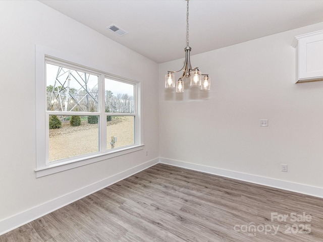 unfurnished dining area with a chandelier, visible vents, light wood-type flooring, and baseboards