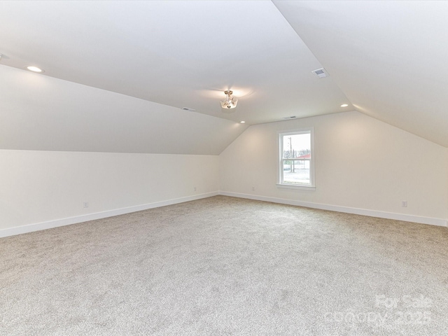 bonus room featuring visible vents, baseboards, light colored carpet, and vaulted ceiling