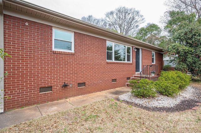 view of home's exterior with brick siding and crawl space