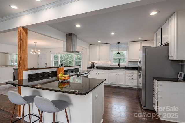 kitchen featuring a breakfast bar, island exhaust hood, stainless steel appliances, a sink, and backsplash