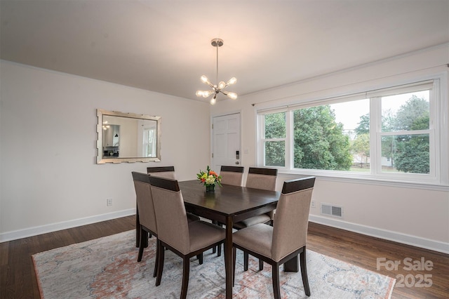 dining space with visible vents, baseboards, a notable chandelier, and wood finished floors