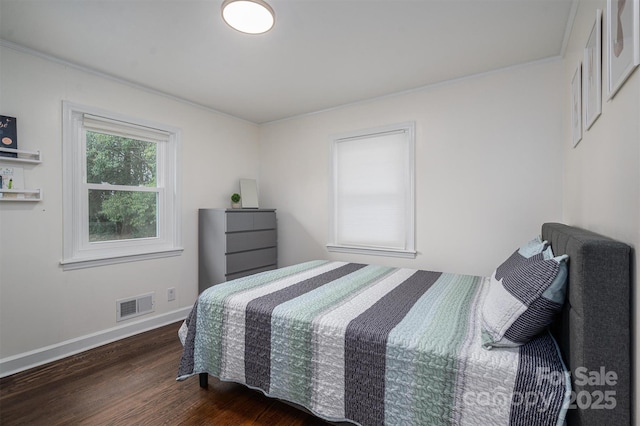 bedroom with wood finished floors, visible vents, and baseboards