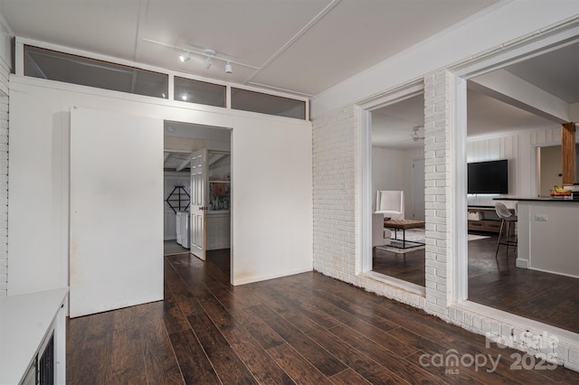 interior space featuring wood-type flooring, brick wall, and rail lighting