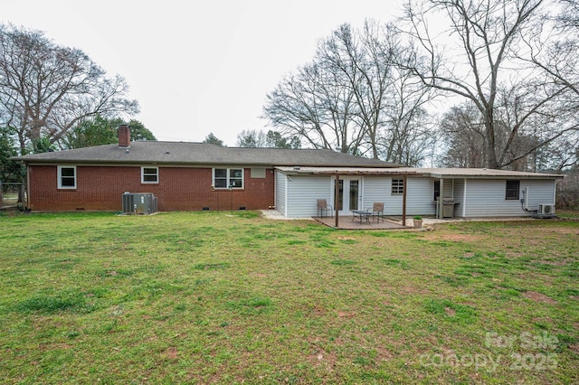 back of property with brick siding, crawl space, a chimney, a yard, and a patio area