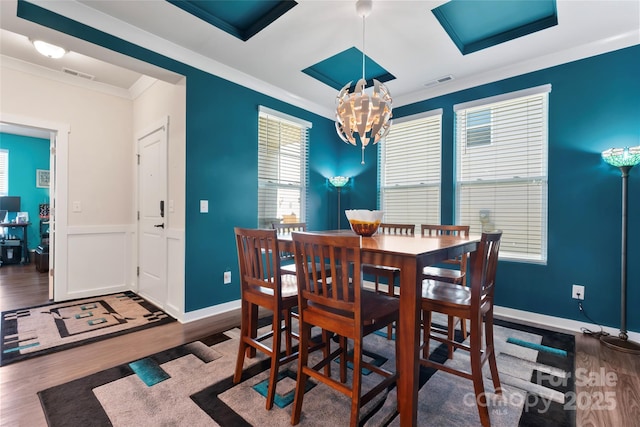 dining area featuring visible vents, an inviting chandelier, wood finished floors, and ornamental molding