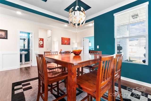 dining room featuring wood finished floors, baseboards, a wainscoted wall, an inviting chandelier, and ornamental molding