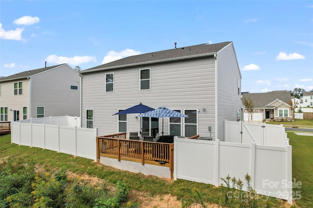 back of house with a gate, fence, a lawn, and a wooden deck