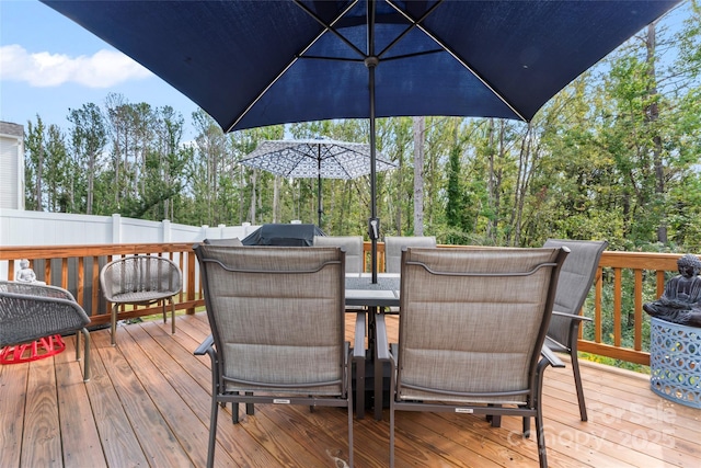 wooden terrace featuring grilling area, outdoor dining space, and fence