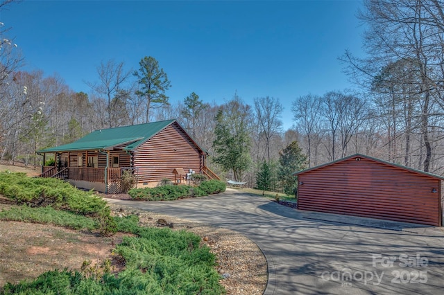 view of side of property featuring log exterior, crawl space, covered porch, driveway, and metal roof