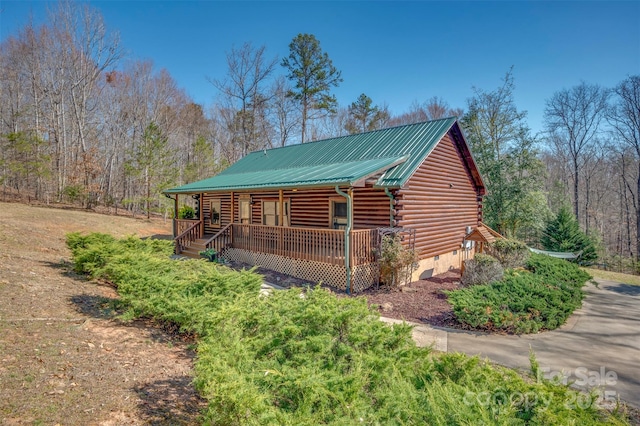 view of front of home featuring covered porch, log exterior, and metal roof