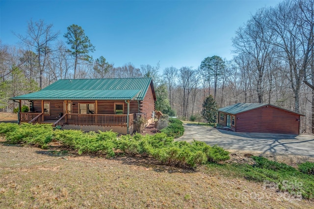 view of side of property with metal roof, covered porch, and log siding