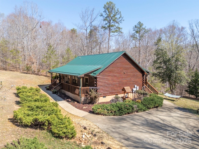 view of side of home featuring stairs, covered porch, and log exterior