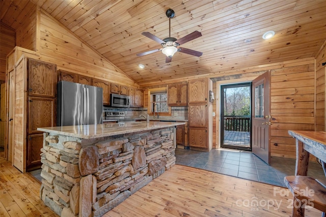 kitchen with appliances with stainless steel finishes, a center island with sink, brown cabinets, wooden ceiling, and lofted ceiling