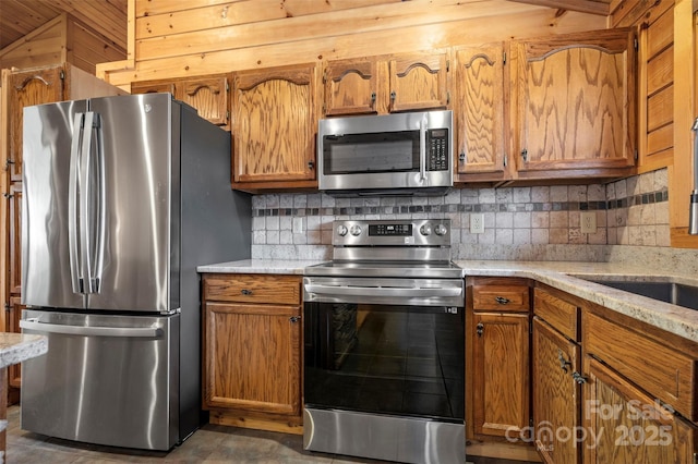 kitchen featuring appliances with stainless steel finishes, tasteful backsplash, and brown cabinetry