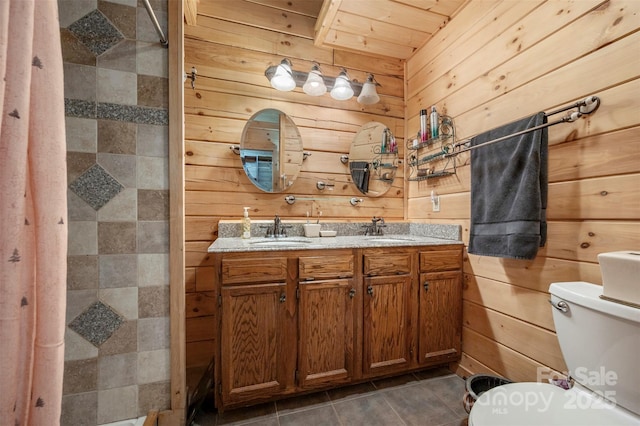 full bathroom featuring a sink, a tile shower, toilet, and wood walls