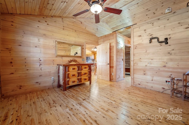 spare room featuring wood-type flooring, ceiling fan, wooden walls, wooden ceiling, and vaulted ceiling