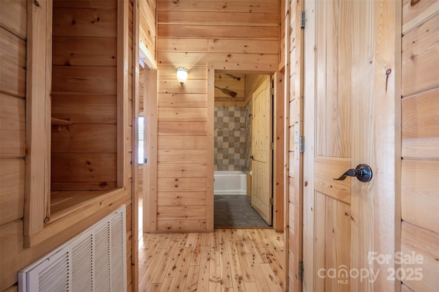 bathroom with wood-type flooring, wood walls, and visible vents