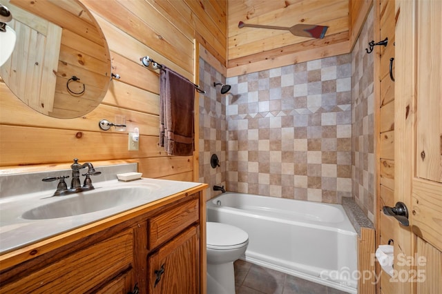 full bathroom with tile patterned flooring, wood walls, vanity, toilet, and shower / bathing tub combination