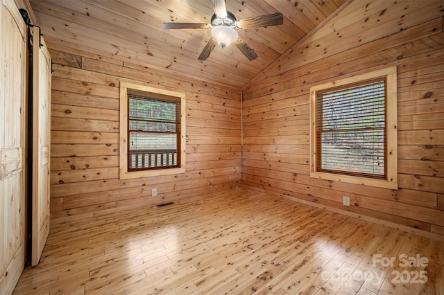 empty room with wooden walls, ceiling fan, vaulted ceiling, and a wealth of natural light