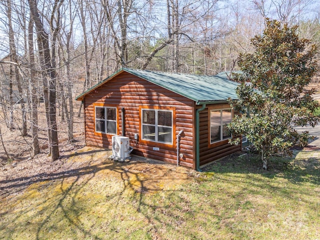 exterior space with ac unit, faux log siding, a front yard, and metal roof