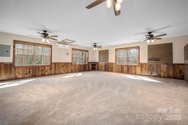 unfurnished living room featuring wood walls, a wall mounted air conditioner, electric panel, and a wainscoted wall