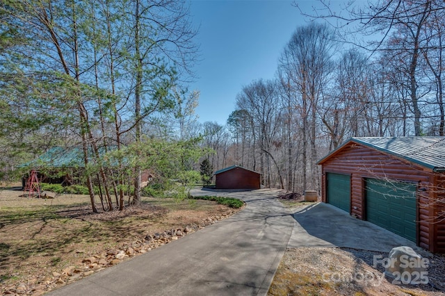 view of home's exterior featuring a detached garage, an outdoor structure, metal roof, and log veneer siding