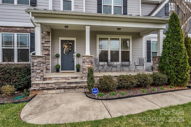 doorway to property with a porch and stone siding