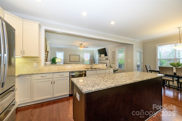 kitchen featuring a peninsula, stainless steel appliances, dark wood-type flooring, and a sink