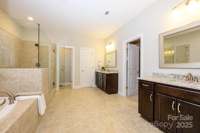 bathroom featuring baseboards, two vanities, a tile shower, a bath, and a sink