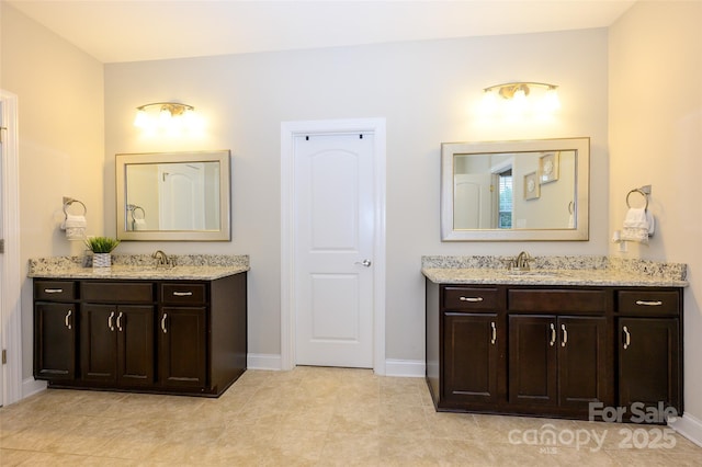 bathroom featuring a sink, baseboards, two vanities, and tile patterned floors