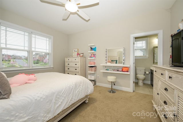 bedroom with light carpet, ensuite bath, baseboards, and light tile patterned flooring