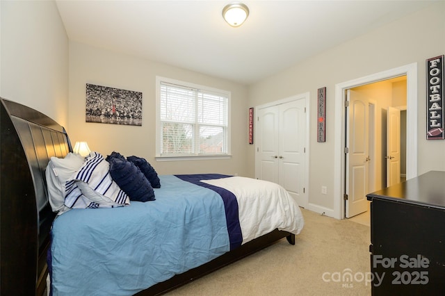 bedroom with a closet, baseboards, and light colored carpet