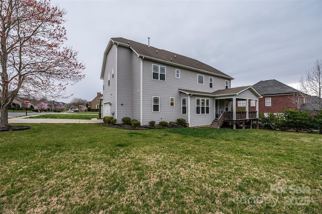 rear view of property featuring a garage, a lawn, and concrete driveway