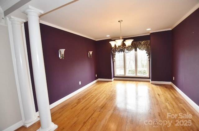 unfurnished room featuring baseboards, crown molding, ornate columns, and wood finished floors