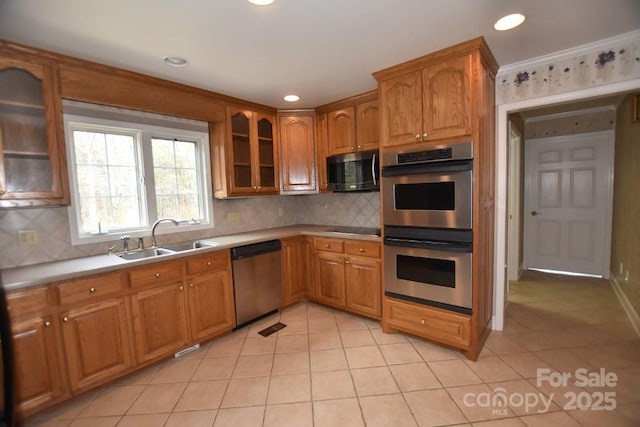 kitchen featuring light countertops, brown cabinetry, appliances with stainless steel finishes, and a sink