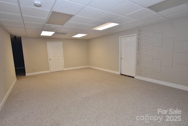 empty room featuring baseboards, a paneled ceiling, and light colored carpet