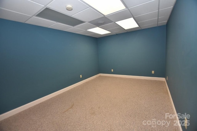 spare room featuring a drop ceiling, baseboards, and carpet floors