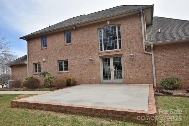 back of house featuring brick siding, french doors, central AC, and a patio