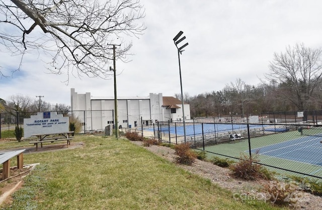 exterior space with a tennis court, a lawn, and fence