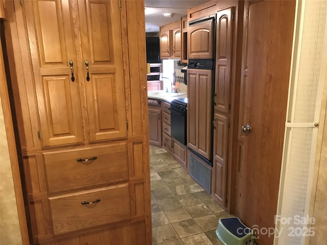 hallway with visible vents, dark tile patterned flooring, and a sink