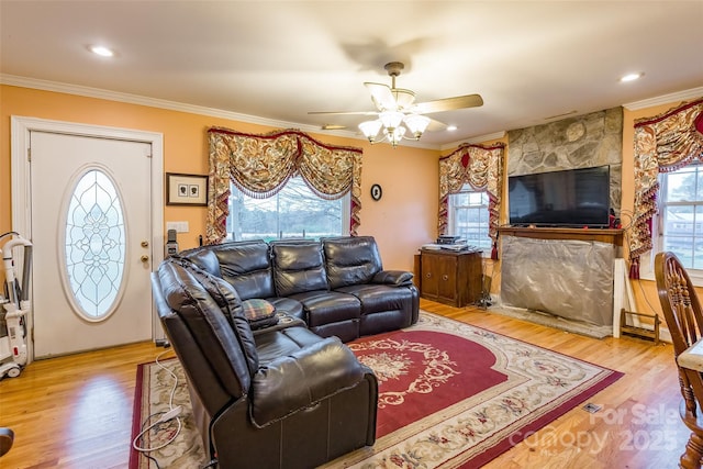 living area featuring crown molding, wood finished floors, and a healthy amount of sunlight