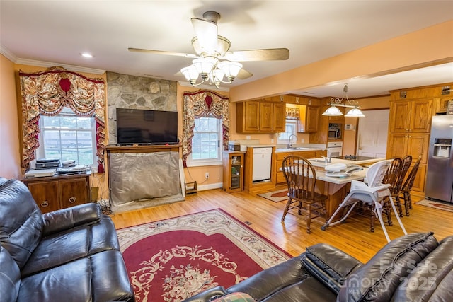 living area with ceiling fan, light wood-style flooring, a healthy amount of sunlight, and ornamental molding