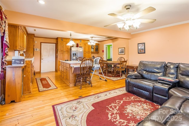 living room featuring crown molding, a ceiling fan, and light wood-type flooring